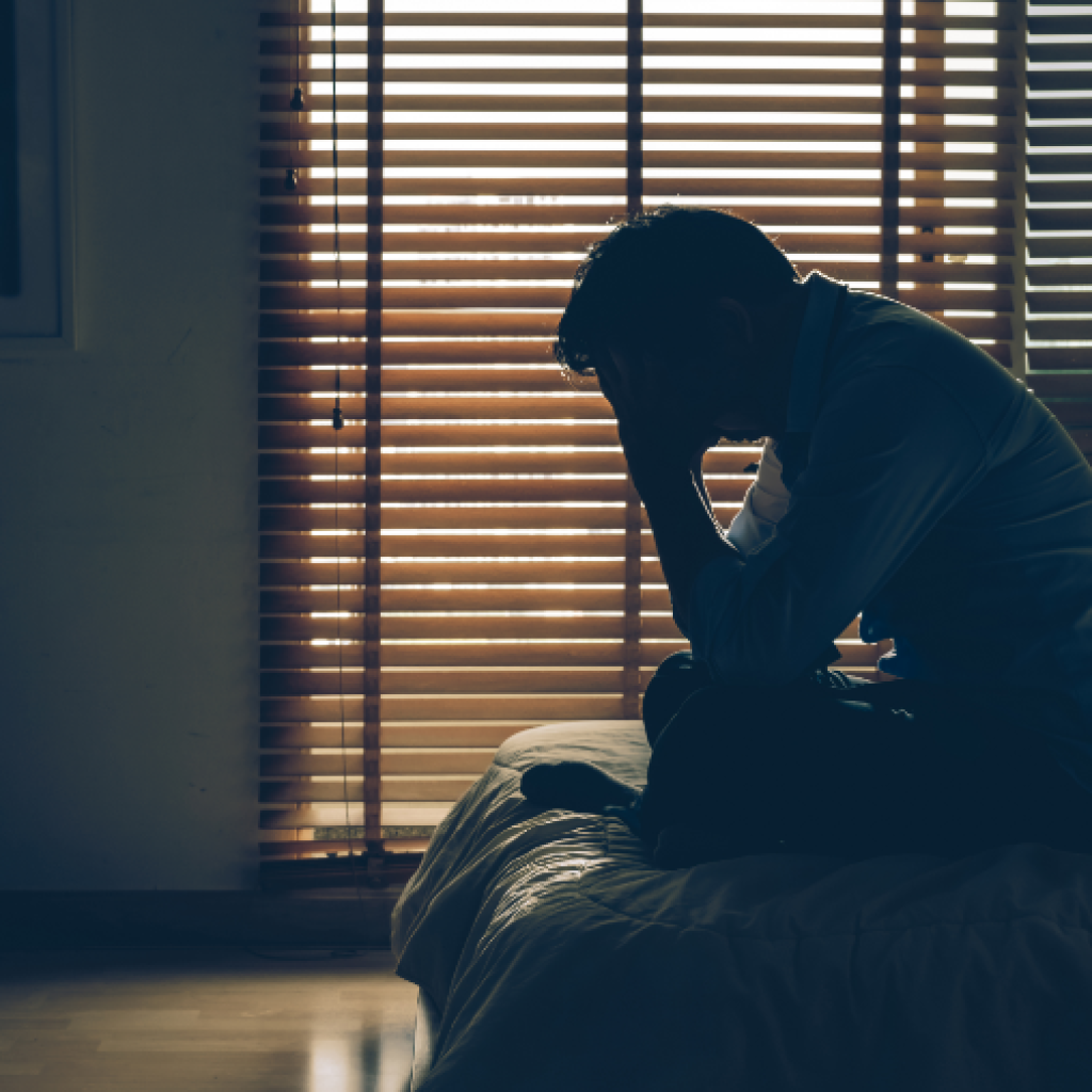 sad businessman sitting head hands bed dark bedroom.png
